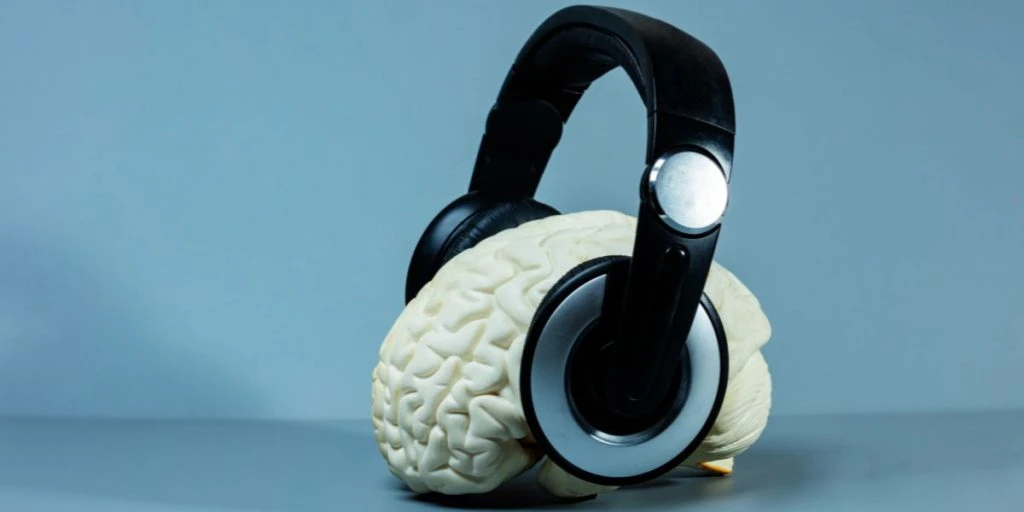 Brain listening to music - headphones on the head view from side on the blue background