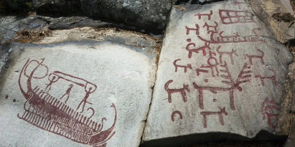 Ancient rock carvings from the Bronze Age near Strömstad. Two men in boats raising spears, with deer and several dogs around them, depict a mythological hunt