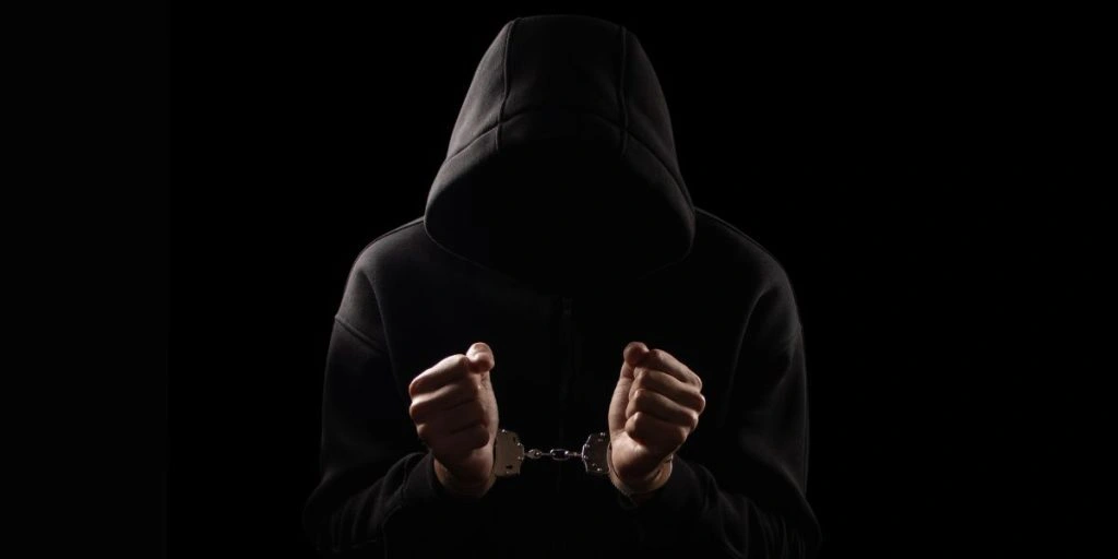 Silhouette of handcuffed male in hoodie, dangerous criminal punished by law