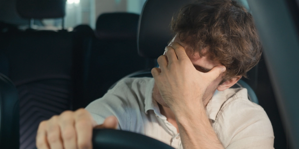 En man sitter i bilen och är trött / arg / chockad