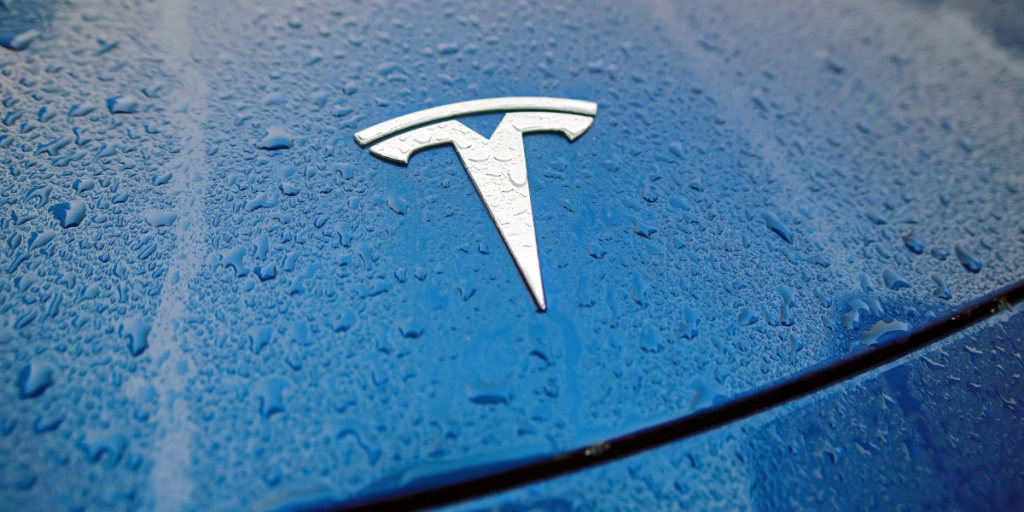 Närbild på en blå tesla 3 motorhuv i regnet