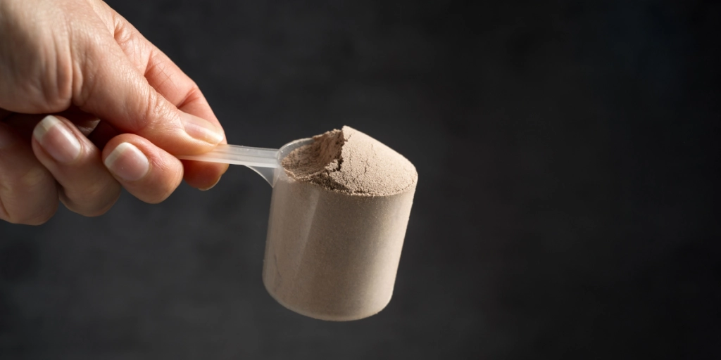 En skopa proteinpulver mot en svart bakgrund