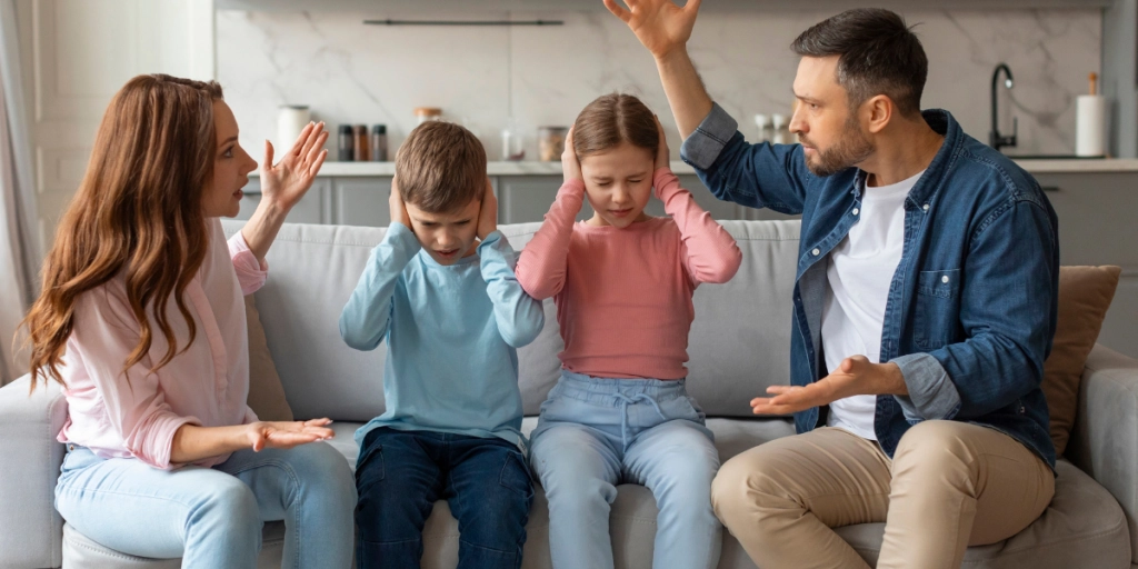 Kvinna och man som diskuterar med barnen mellan sig i soffan