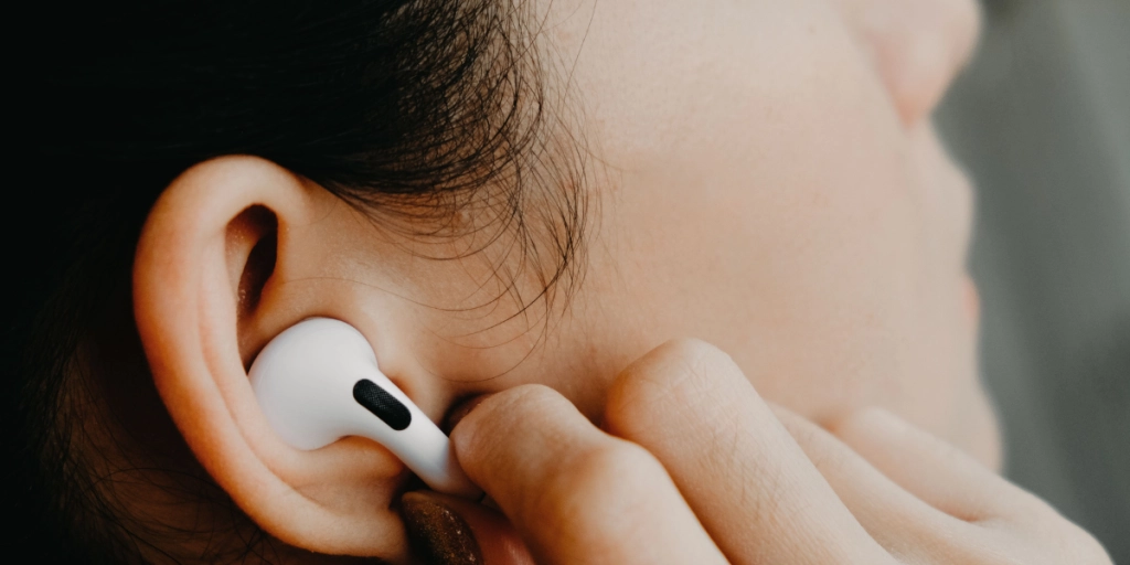 Ung kvinna med AirPods i öronen / Apple