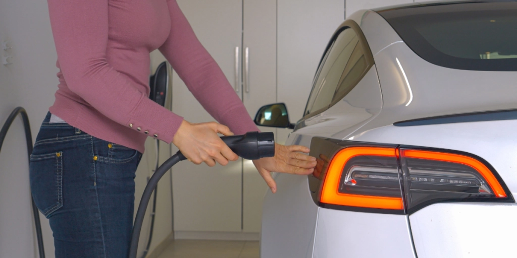Kvinna laddar sin vita Tesla model 3 hemma
